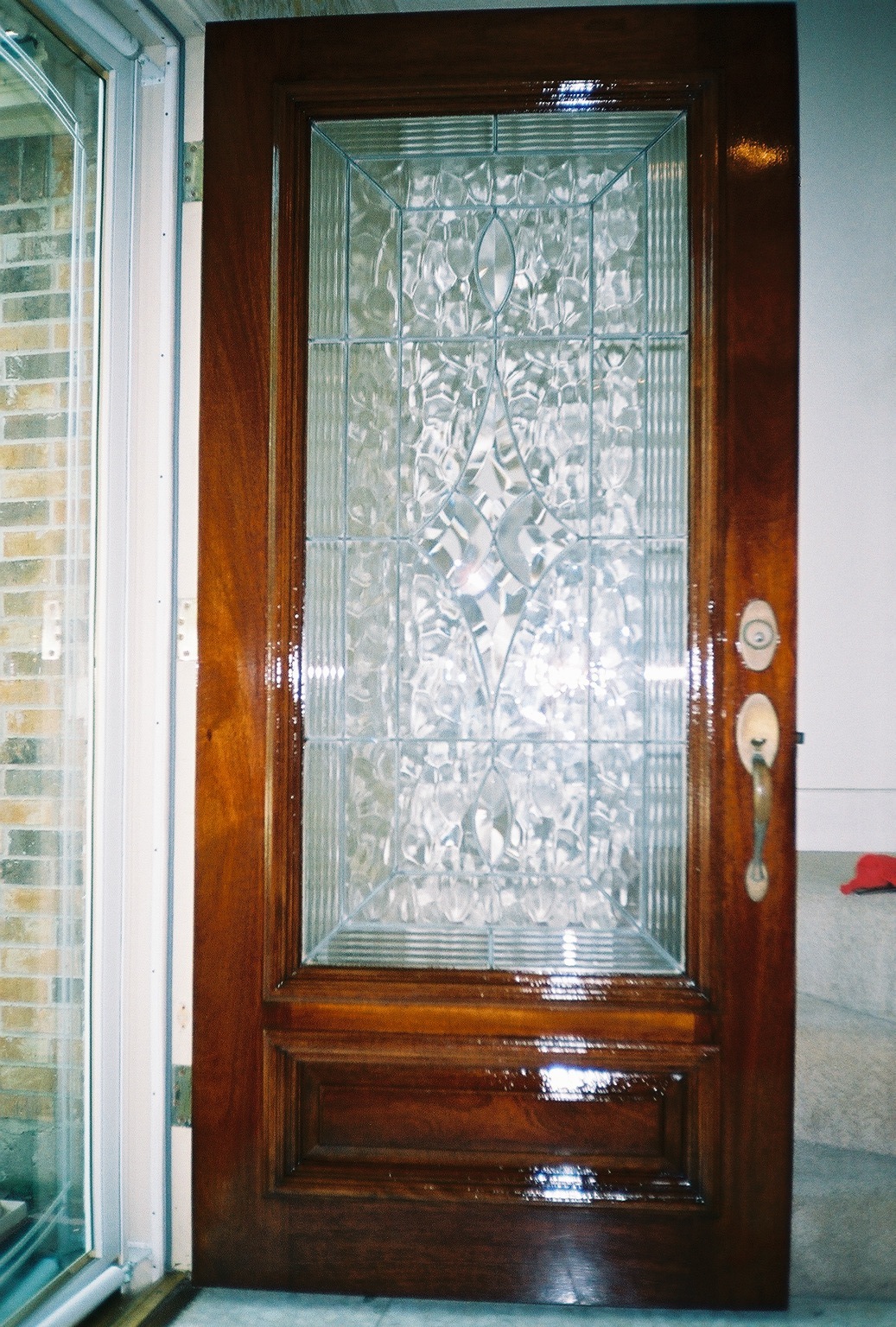 A richly refinished mahogany front door with ornate beveled glass, restored to a glossy like-new finish
